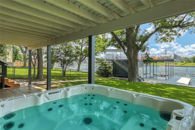 view of swimming pool featuring a hot tub, a water view, a yard, and a patio