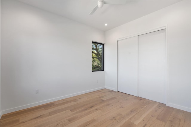 unfurnished bedroom with light wood-type flooring, ceiling fan, and a closet