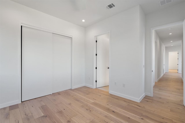 unfurnished bedroom with light wood-type flooring and a closet