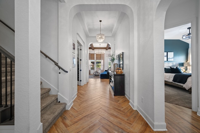 foyer featuring a raised ceiling, parquet floors, and a chandelier