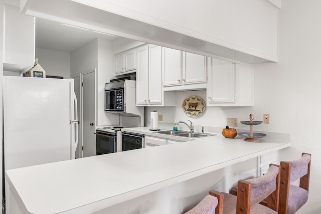 kitchen featuring sink, white cabinets, kitchen peninsula, electric range, and a breakfast bar