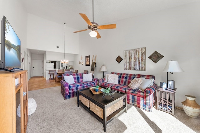 carpeted living room featuring ceiling fan with notable chandelier and high vaulted ceiling