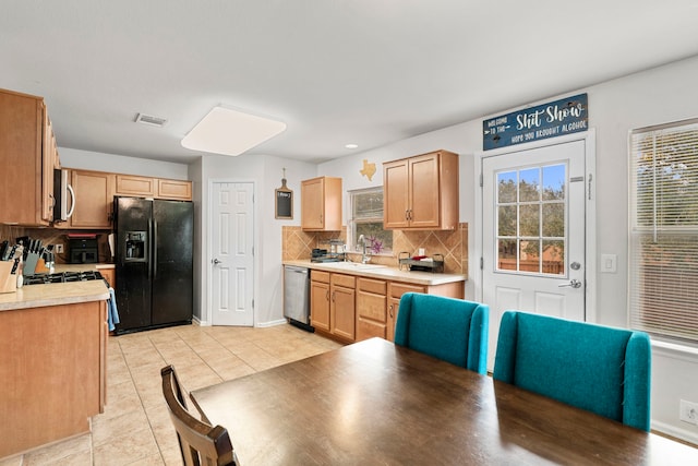 kitchen featuring appliances with stainless steel finishes, light brown cabinets, tasteful backsplash, sink, and light tile patterned floors