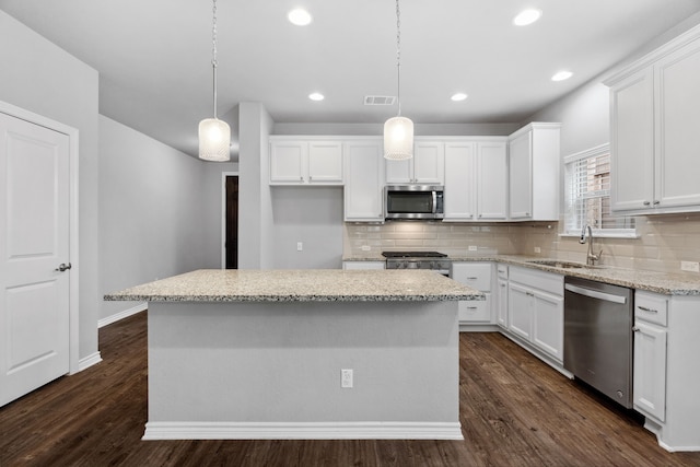 kitchen featuring appliances with stainless steel finishes, pendant lighting, and white cabinetry