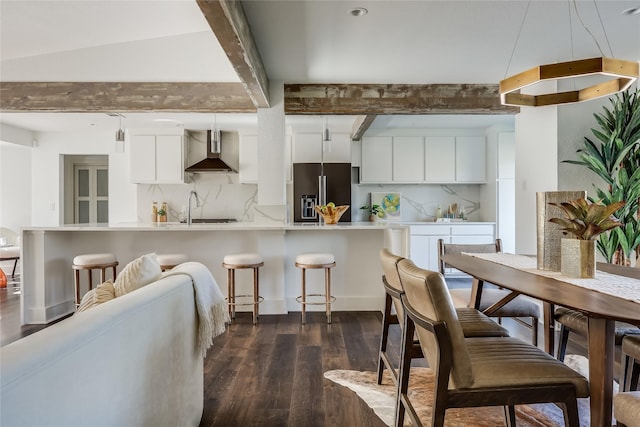 kitchen with white cabinets, backsplash, high end fridge, and wall chimney exhaust hood