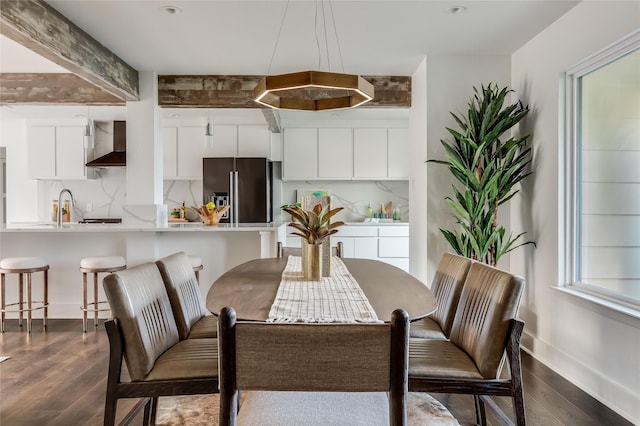 dining space with beam ceiling, dark hardwood / wood-style flooring, and sink