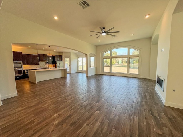 312 Brave Face St, Leander, TX 78641 - unfurnished living room with dark wood-style floors, a ceiling fan, arched walkways, recessed lighting, and a glass covered fireplace