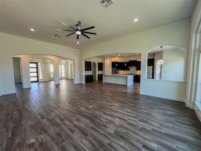 unfurnished living room with ceiling fan and dark hardwood / wood-style flooring