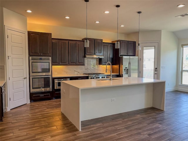 312 Brave Face St, Leander, TX 78641 - kitchen featuring appliances with stainless steel finishes, dark wood finished floors, recessed lighting, an island with sink, and decorative backsplash