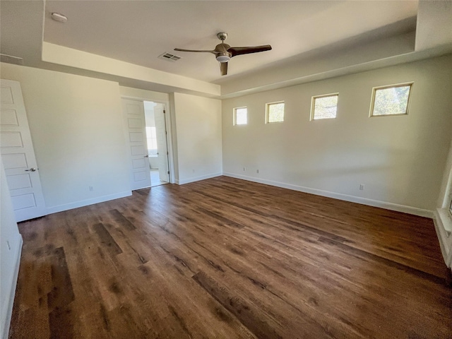 spare room with dark hardwood / wood-style flooring, a raised ceiling, and ceiling fan