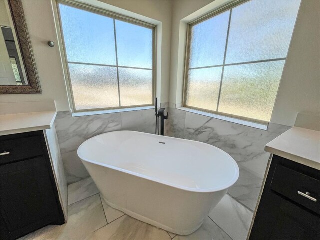 312 Brave Face St, Leander, TX 78641 - full bathroom with vanity, tile walls, a wainscoted wall, a freestanding tub, and marble finish flooring