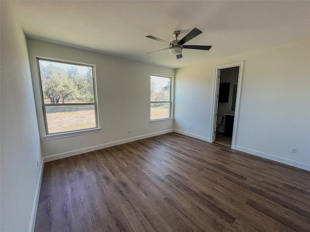 empty room with ceiling fan, a wealth of natural light, and dark wood-type flooring