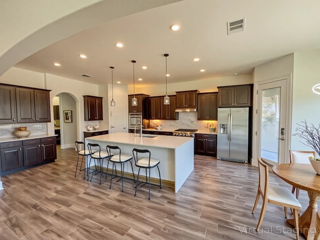 312 Brave Face St, Leander, TX 78641 - kitchen featuring stainless steel appliances, arched walkways, dark brown cabinets, backsplash, and recessed lighting
