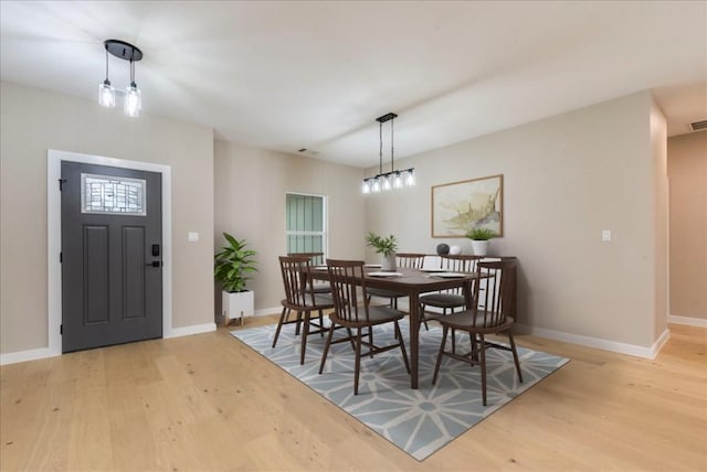 dining area with baseboards, light wood finished floors, and visible vents