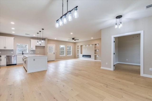 kitchen with pendant lighting, white cabinetry, a center island, stainless steel dishwasher, and ceiling fan