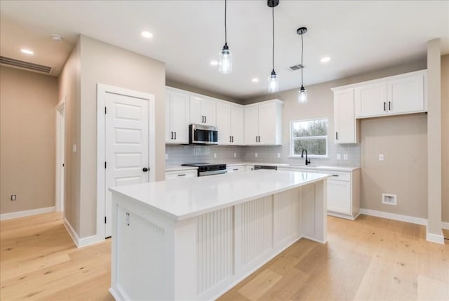 kitchen with stainless steel appliances, sink, a kitchen island, and white cabinets