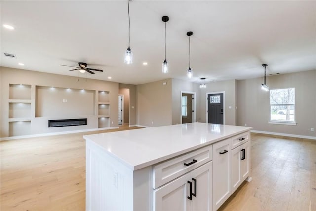 kitchen featuring hanging light fixtures, a center island, white cabinets, and light hardwood / wood-style floors