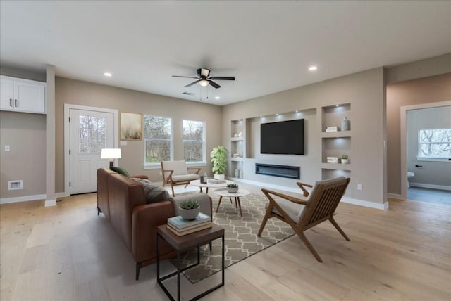 living area featuring ceiling fan, built in features, baseboards, light wood finished floors, and recessed lighting