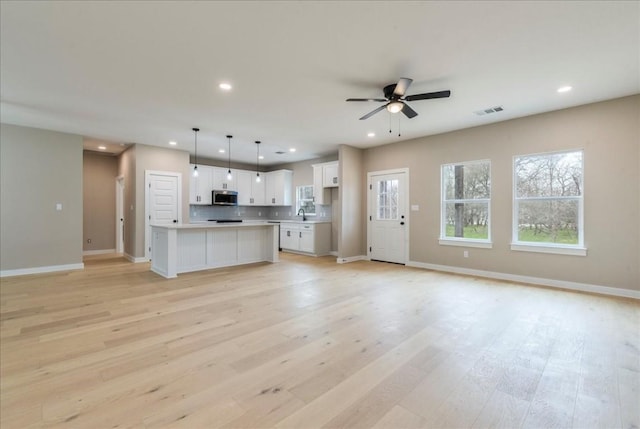 kitchen featuring white cabinetry, a center island, hanging light fixtures, and light wood-type flooring