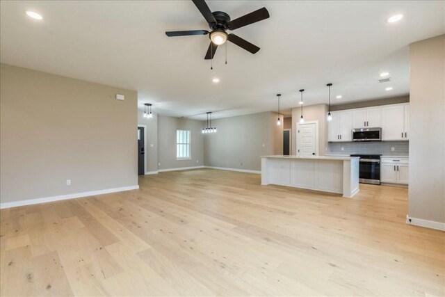 unfurnished living room featuring ceiling fan and light hardwood / wood-style flooring