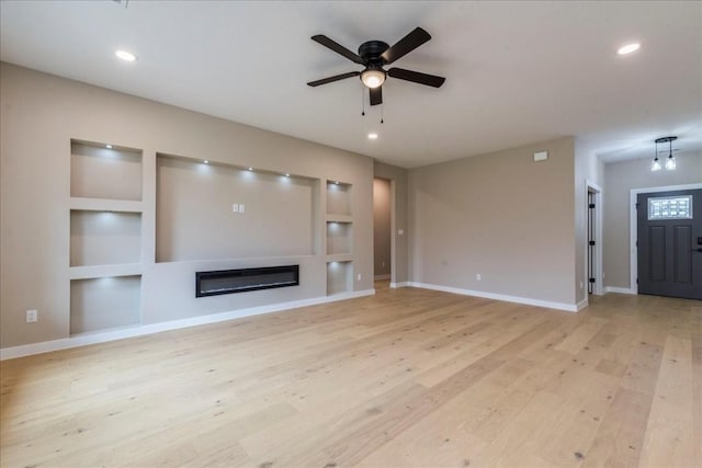 unfurnished living room featuring built in shelves, light hardwood / wood-style flooring, and ceiling fan