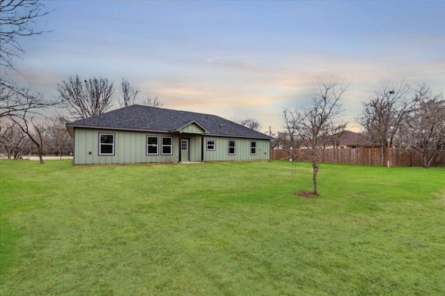 back house at dusk featuring a yard