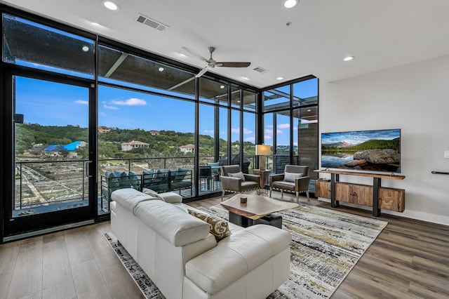 living room featuring ceiling fan, hardwood / wood-style flooring, and a wall of windows