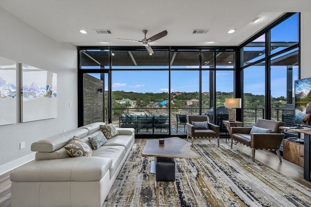 living area featuring floor to ceiling windows, visible vents, a ceiling fan, and wood finished floors