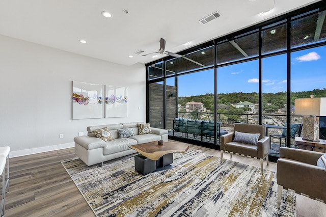 living room featuring ceiling fan, a high ceiling, hardwood / wood-style flooring, and expansive windows