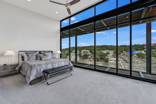 carpeted bedroom with floor to ceiling windows, a high ceiling, and ceiling fan