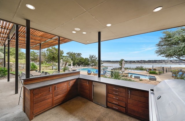 view of patio featuring a water view, exterior kitchen, and area for grilling