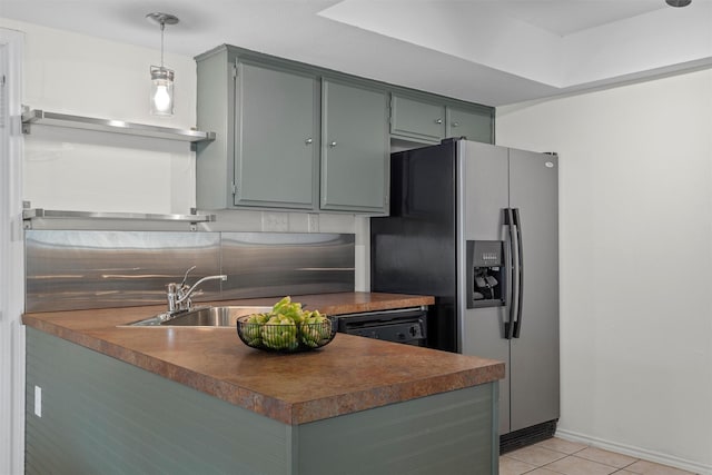 kitchen featuring backsplash, sink, hanging light fixtures, light tile patterned floors, and stainless steel fridge