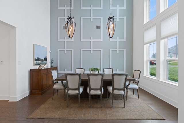 dining area featuring a towering ceiling and dark hardwood / wood-style flooring