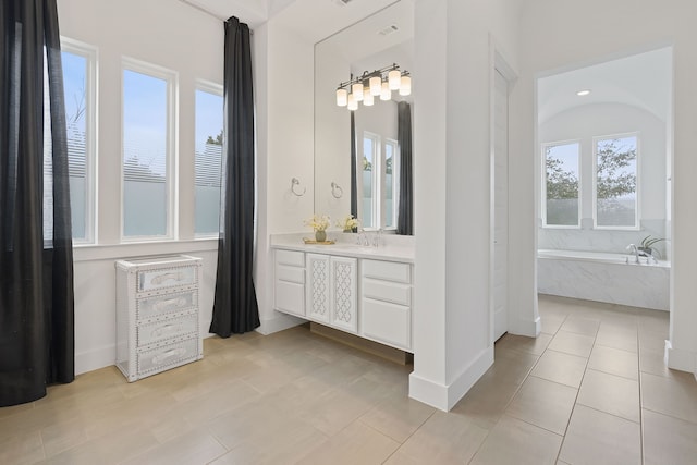 bathroom with a relaxing tiled tub, vanity, and tile patterned floors