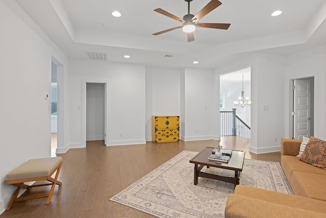 living room featuring a raised ceiling, ceiling fan with notable chandelier, and hardwood / wood-style floors