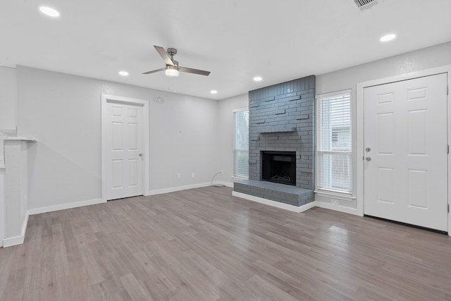 unfurnished living room featuring light hardwood / wood-style floors, ceiling fan, and a brick fireplace