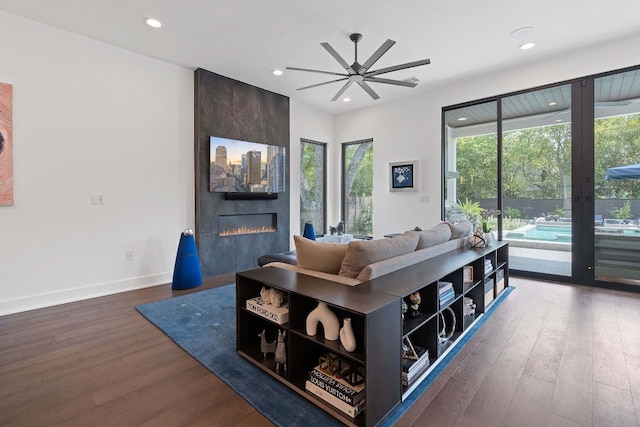 living area with recessed lighting, a fireplace, wood finished floors, a ceiling fan, and baseboards