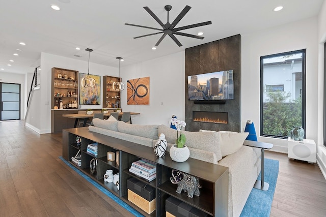 living area featuring a large fireplace, dark wood-style flooring, baseboards, and recessed lighting