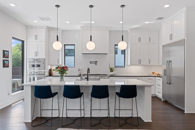 kitchen with appliances with stainless steel finishes, visible vents, and dark wood finished floors