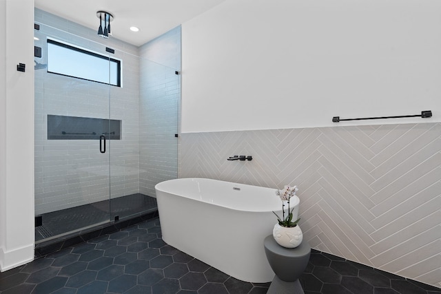 bathroom featuring a freestanding tub, a wainscoted wall, tile walls, tile patterned floors, and a stall shower