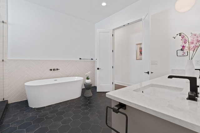 bathroom featuring vanity, tile walls, a freestanding bath, wainscoting, and tile patterned floors