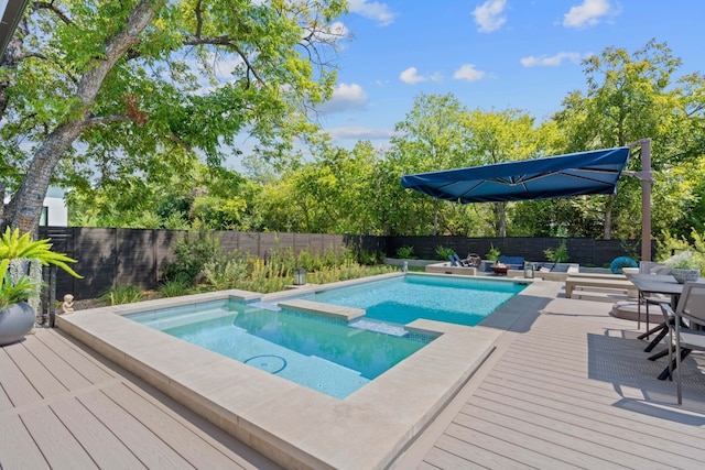 view of pool with a fenced backyard, a wooden deck, and a pool with connected hot tub