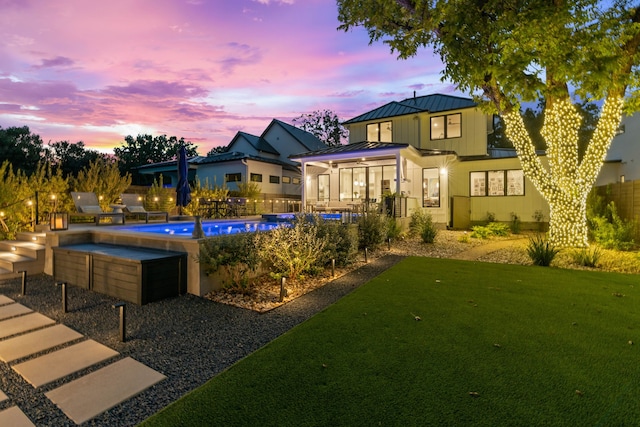 back of property featuring a fenced in pool, metal roof, a standing seam roof, fence, and a yard