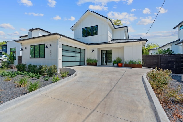 modern farmhouse featuring driveway, metal roof, an attached garage, a standing seam roof, and fence