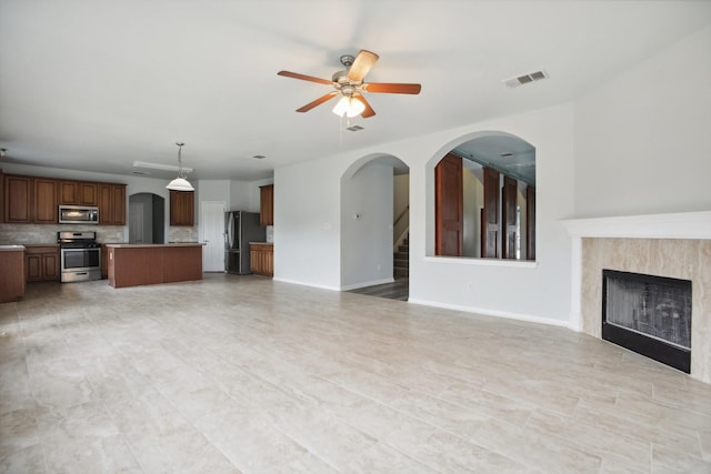 unfurnished living room featuring a fireplace and ceiling fan