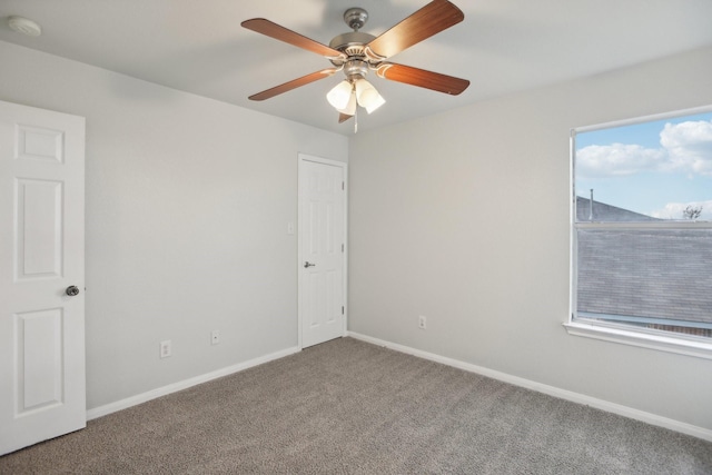 spare room featuring ceiling fan, a wealth of natural light, and carpet