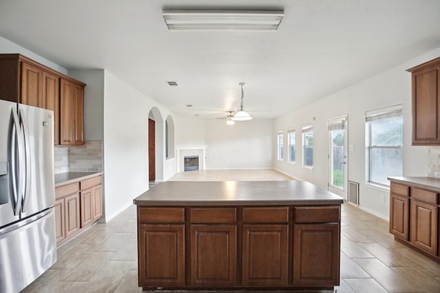 kitchen featuring ceiling fan, stainless steel fridge, tasteful backsplash, and a center island