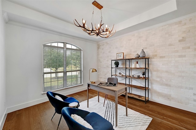 home office featuring brick wall, a raised ceiling, a notable chandelier, crown molding, and dark hardwood / wood-style flooring