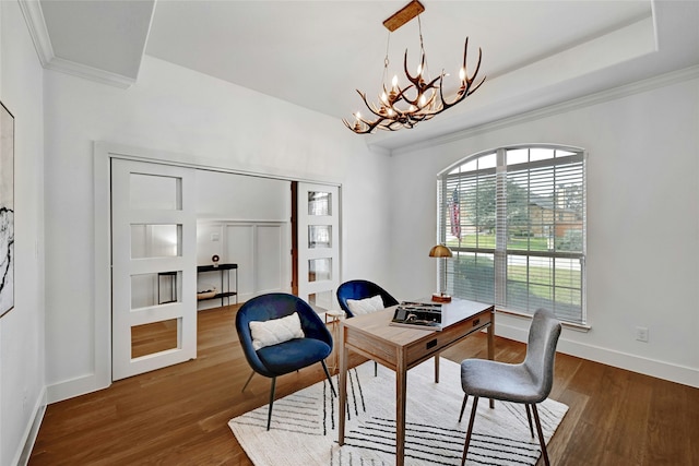 office area with an inviting chandelier, a raised ceiling, ornamental molding, and dark hardwood / wood-style flooring