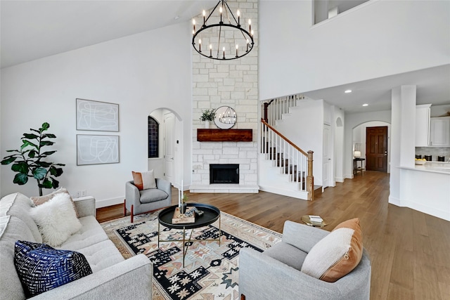 living room featuring a fireplace, high vaulted ceiling, dark wood-type flooring, and a notable chandelier